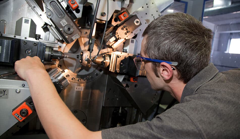 man operating cnc equipment to manufacture springs