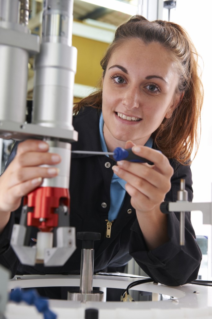 Apprentice Female Engineer Working On Machine In Factory