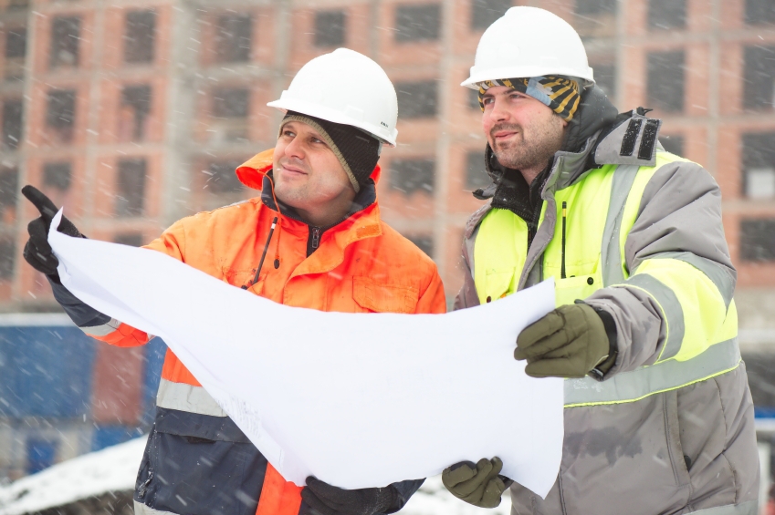 Two engineers looking at construction plans in winter