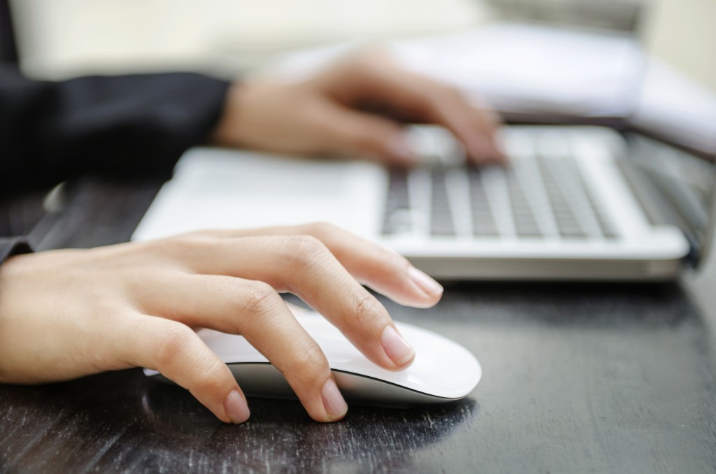 Close-up of a woman's hands on a mouse and keyboard