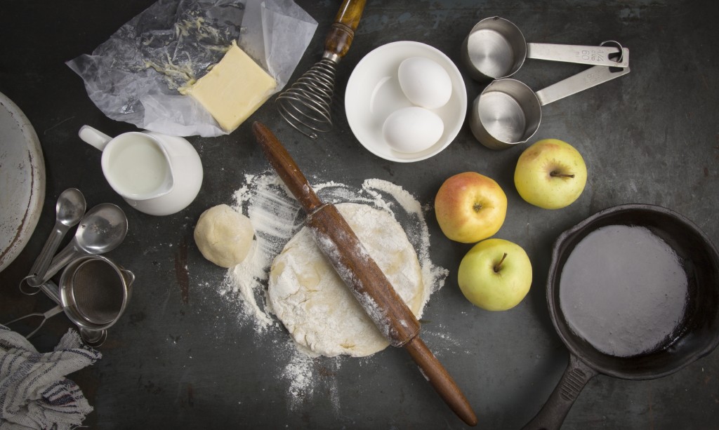 cooking with eggs, apples, flour and pastry, along with a number of utensils 