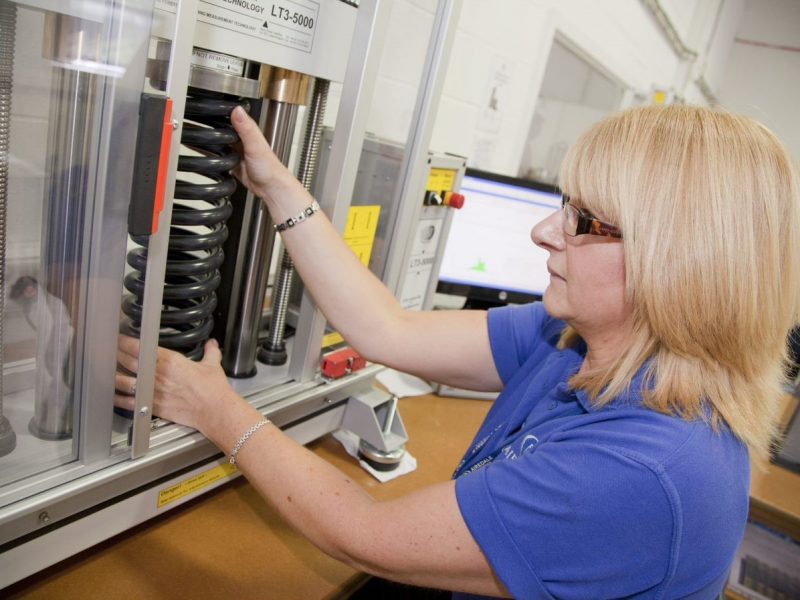 woman wearing goggles testing spring resistance on a machine