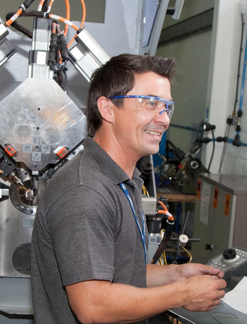 Airedale springs employee standing at a cnc machine