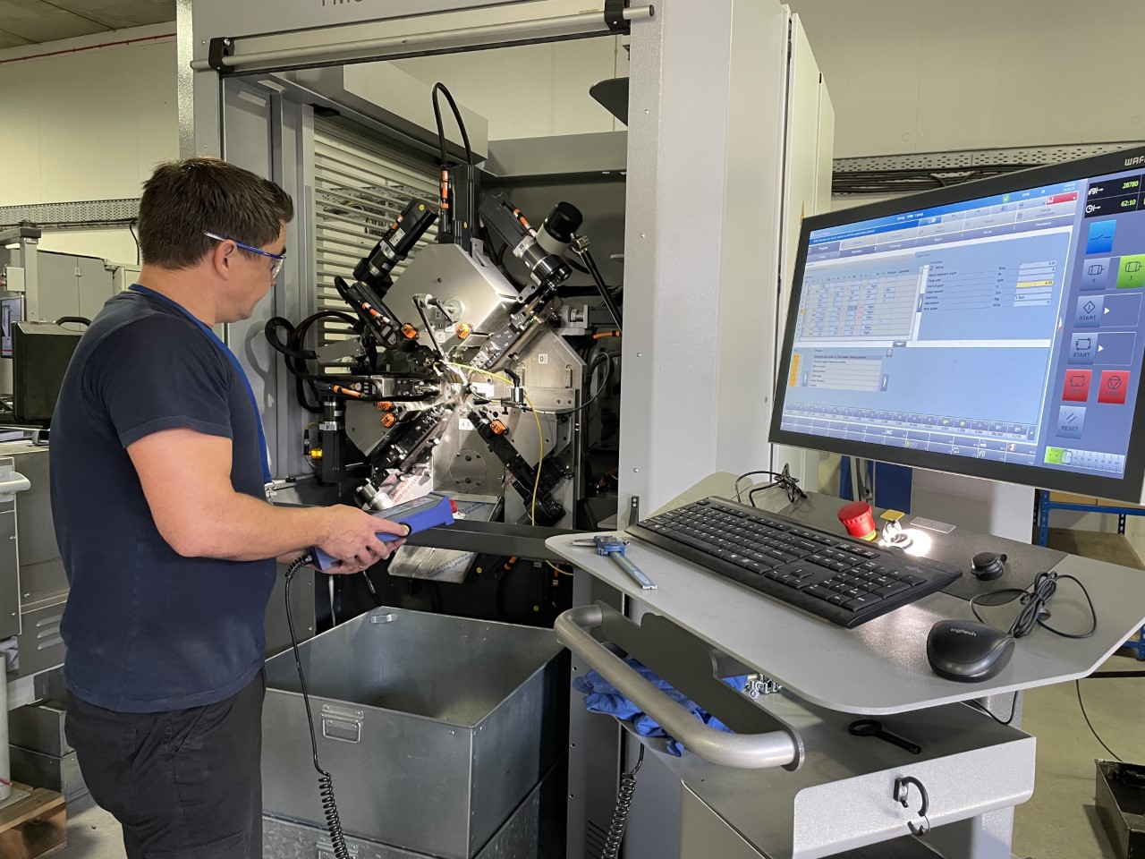 men working with a machine in front of a big pc